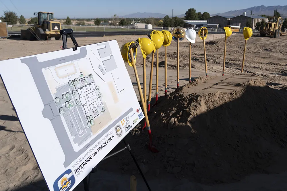 Construction site with plan prominently displayed next to row of hard hats
